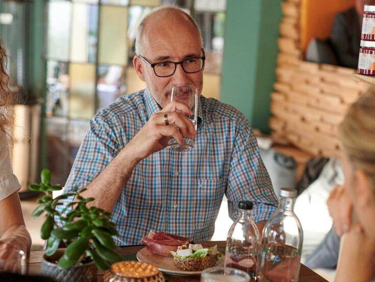 Mann trinkt Wasser in Café