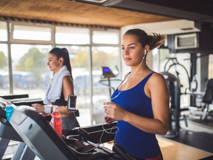 Zwei Personen trainieren auf einem Laufband mit Getränken