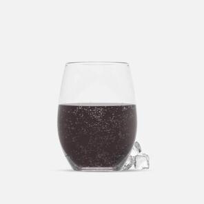 Glas mit Cola vor beigefarbenen Hintergrund
