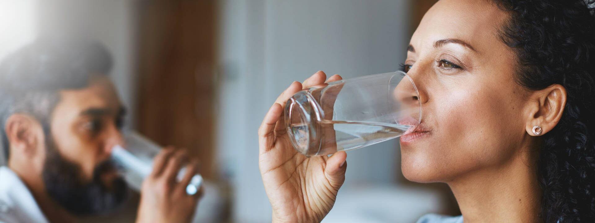 Frau und Mann trinken Wasser aus einem Glas