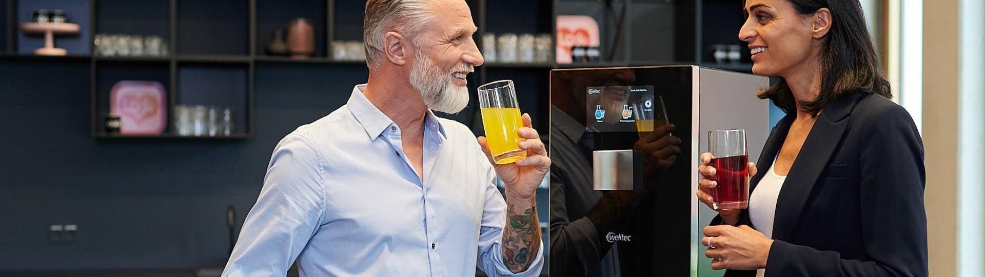 Menschen trinken Wasser mit Sirup vor dem welltec Aqua Choice Wasserspender