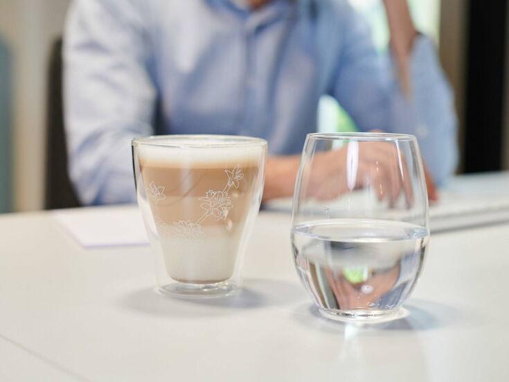 Ein Latte Macchiato und Glas Wasser serviert auf dem Schreibtisch