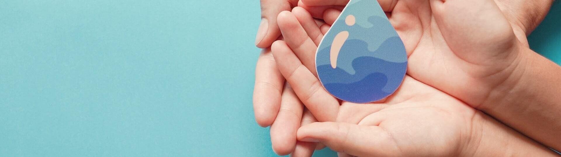 Zwei Hände schützen einen Wassertropfen
