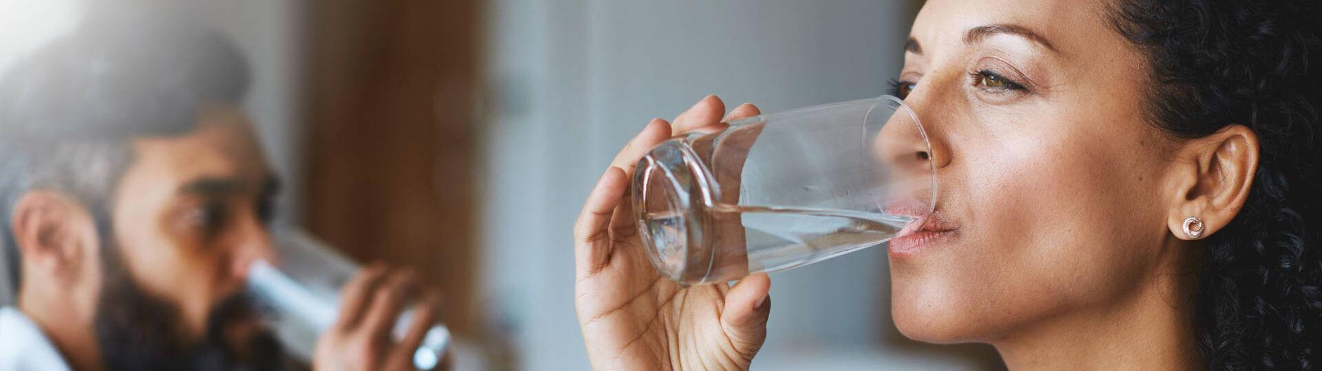 Frau und Mann trinken Wasser aus einem Glas