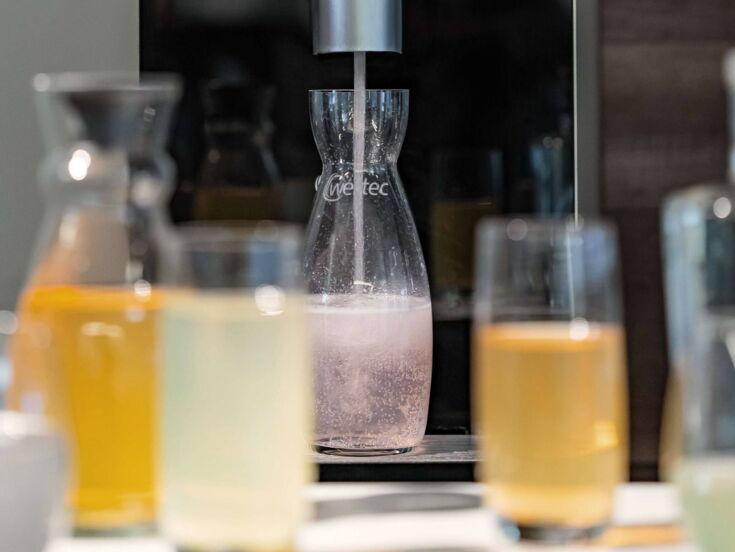 Eine Karaffe steht unter dem Auslauf und wird mit Sirup befüllt