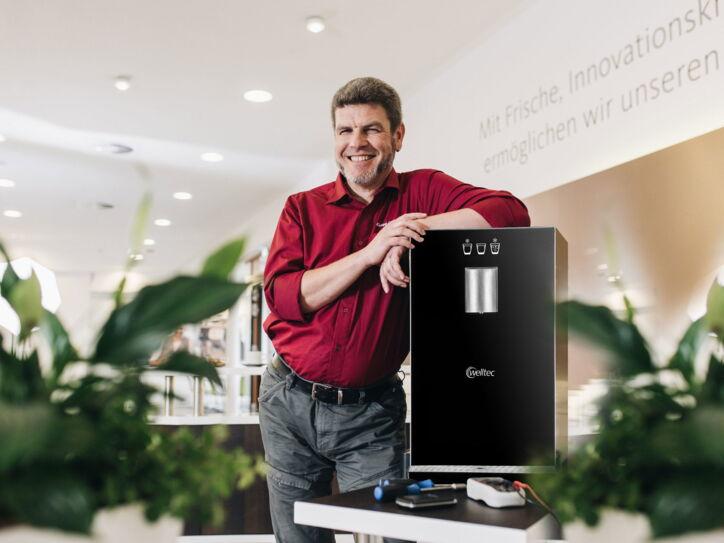 Servicemitarbeiter steht neben einem Frischwasserspender