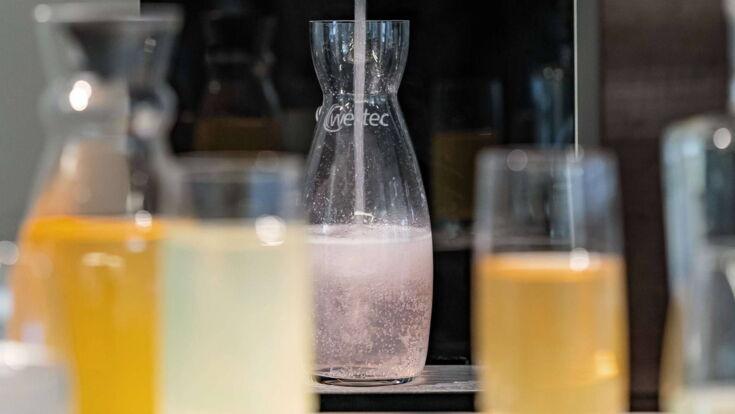 Eine Karaffe steht unter dem Auslauf und wird mit Sirup befüllt