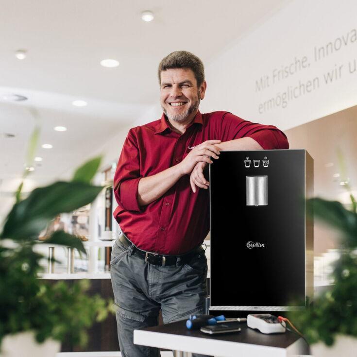 Servicemitarbeiter steht neben einem Frischwasserspender