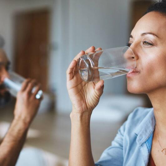 Frau und Mann trinken Wasser aus einem Glas